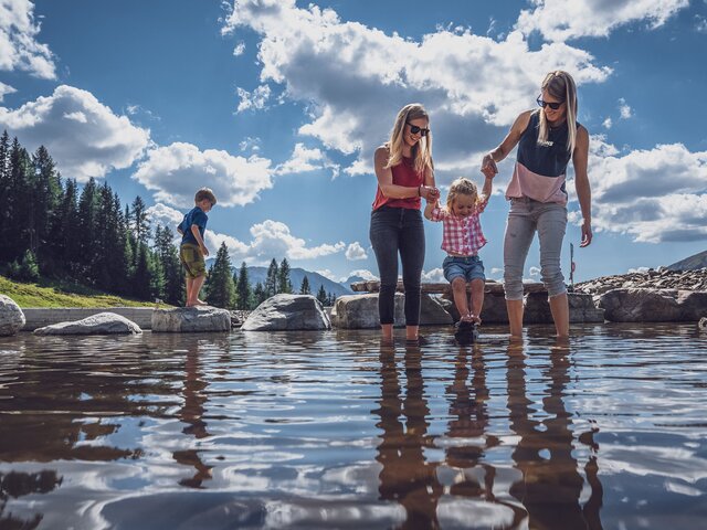 Familie kühlt Füsse ab im Bergsee  | © Davos Klosters Mountains