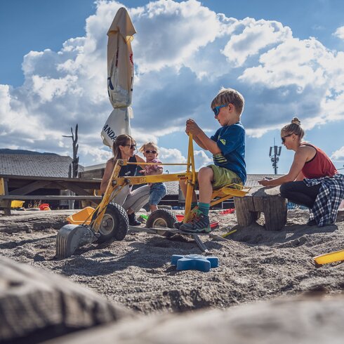 2 children and 2 adults are in the sandpit playing together.  | © Davos Klosters Mountains