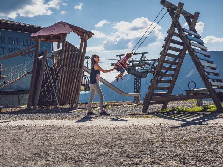 Kleinkind auf Schaukel wird von seiner Mutter angeschaukelt  | © Davos Klosters Mountains 