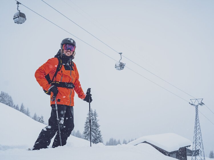 Glücklich steht der Skifahrer im Schnee, hinter ihm die Gondeln des Rinerhorns. | © Davos Klosters Mountains