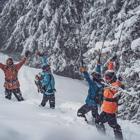 A group of freeriders stand in the deep snow on the Rinerhorn and celebrate the fact that it is snowing.  | © Davos Klosters Mountains
