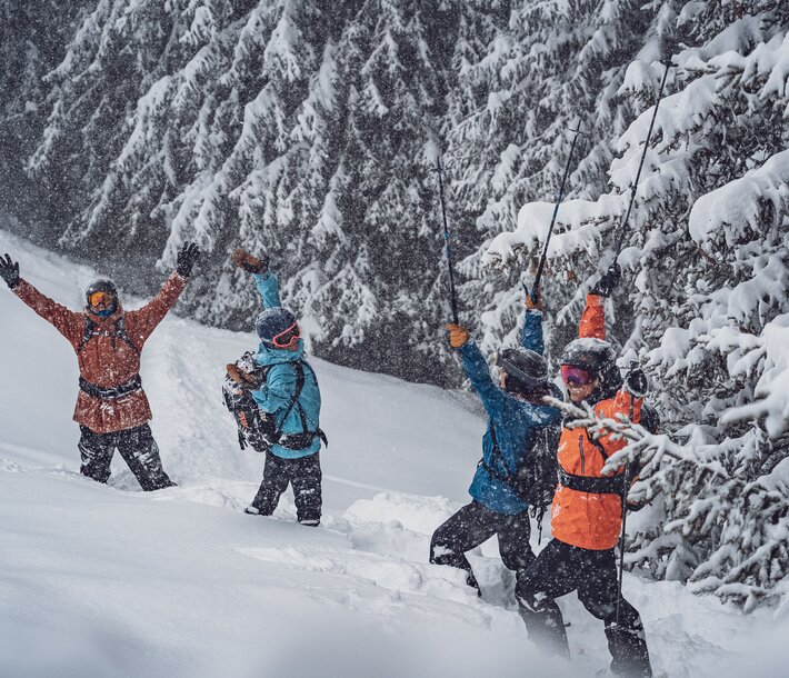 EIne Gruppe Freerider stehen im Tiefschnee auf dem Rinerhorn und feiern, dass es schneit.  | © Davos Klosters Mountains