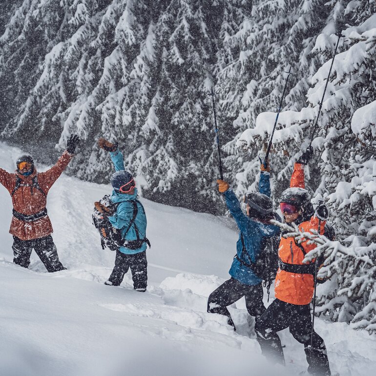 EIne Gruppe Freerider stehen im Tiefschnee auf dem Rinerhorn und feiern, dass es schneit.  | © Davos Klosters Mountains