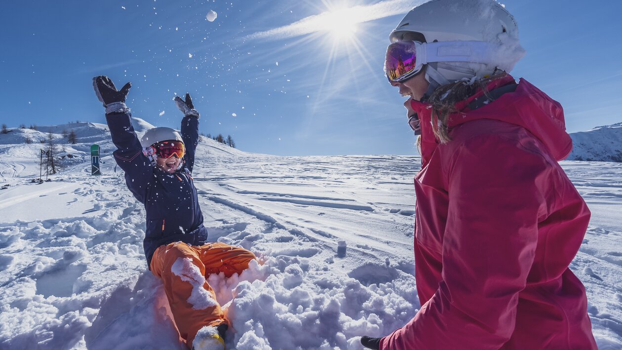 Mutter und Tochter spielen im Tiefschnee bei Sonnenschein. | © Davos Klosters Mountains