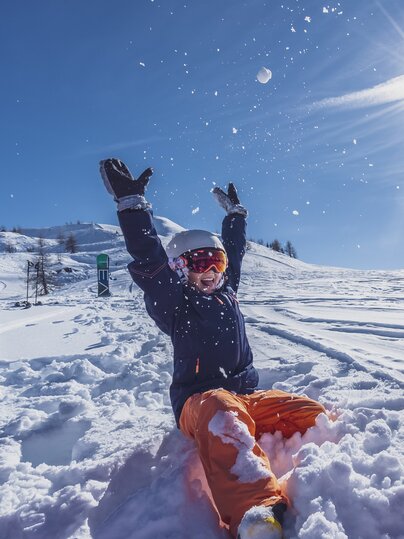 Mutter und Tochter spielen im Tiefschnee bei Sonnenschein. | © Davos Klosters Mountains