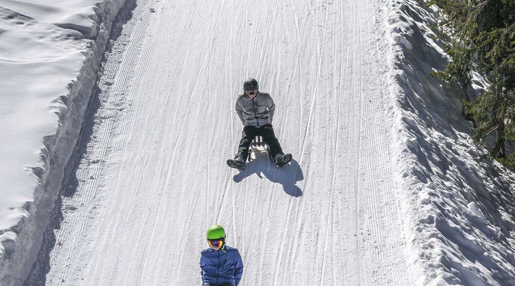 Sled run Rinerhorn | © Davos Klosters Mountains Group of young guys on sledge whiz down the prepared sled run. | © Davos Klosters Mountains