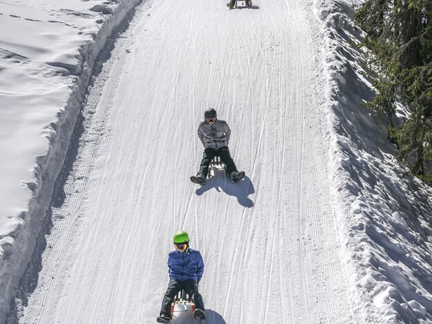 Gruppe junge Schlittler sausen die präparierte Schlittelpiste hinunter. | © Davos Klosters Mountains