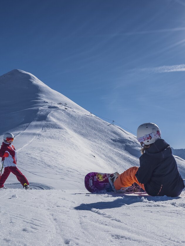 Ab auf die Pisten | © Davos Klosters Mountains Mädchen wartet auf Ihre Schwester um die Piste hinunter zu sausen. | © Davos Klosters Mountains