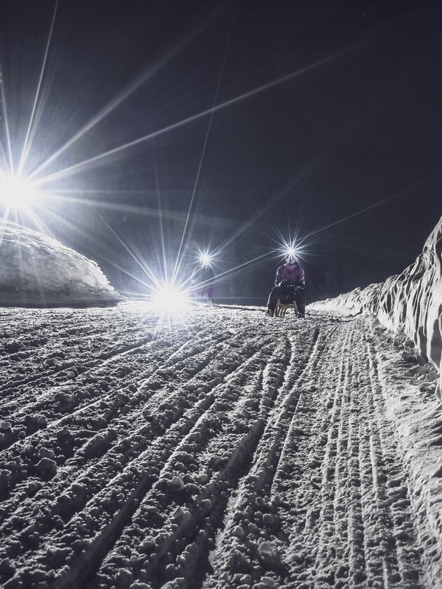 Nachtschlitteln Rinerhorn | © Davos Klosters Mountains Mädchen mit Taschenlampe schlittelt auf der Nachtpiste hinunter. | © Davos Klosters Mountains