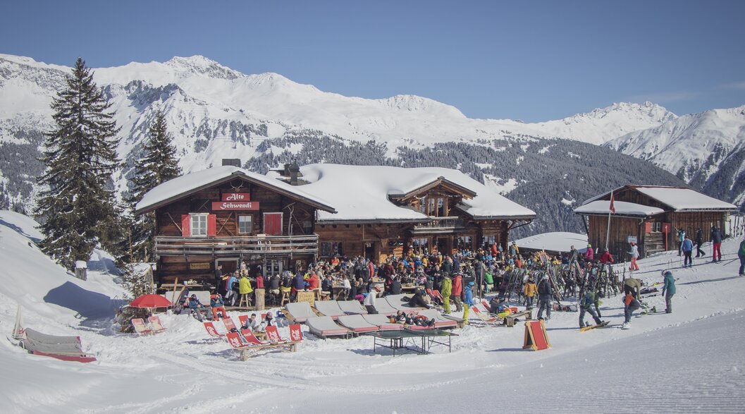 Mountain restaurant alte Schwendi with a filled terrace on a sunny winter day. | © Davos Klosters Mountains