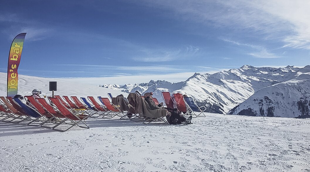Red deckchairs are lined up on the viewing terrace of Gruobenalp. | © Davos Klosters Mountains