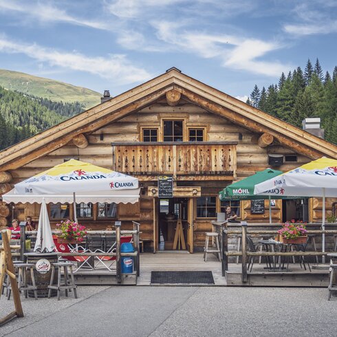 Aussenansicht auf das rustikale Blockhuus mit Sonnenterrasse im Sommer. | © Davos Klosters Mountains
