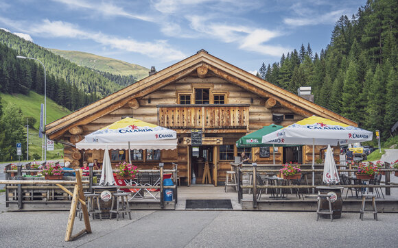 Aussenansicht auf das rustikale Blockhuus mit Sonnenterrasse im Sommer. | © Davos Klosters Mountains