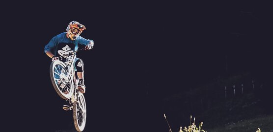 Sprung eines Mountainbikers auf der Gotschna Freeride Strecke auf Parsenn.