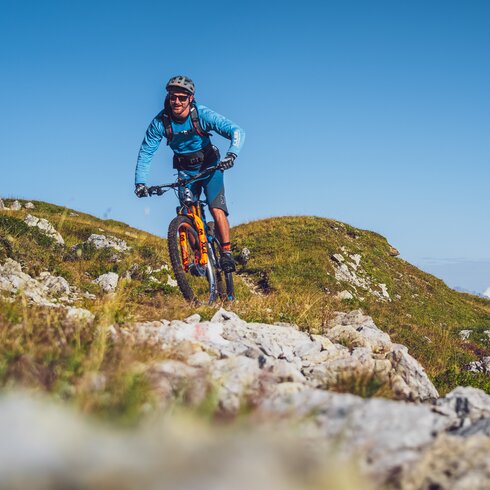 Biker in blauer Kleidung und mit orangem Mountainbike auf Gotschna Parsenn. | © Davos Klosters Mountains