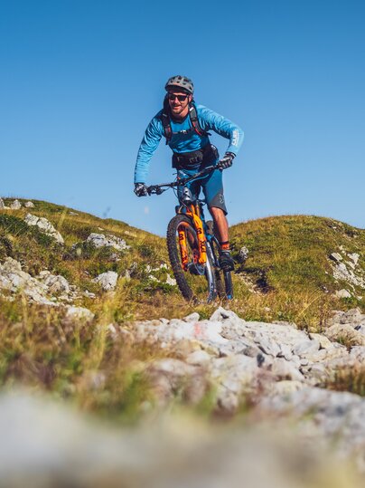 Biker in blauer Kleidung und mit orangem Mountainbike auf Gotschna Parsenn. | © Davos Klosters Mountains