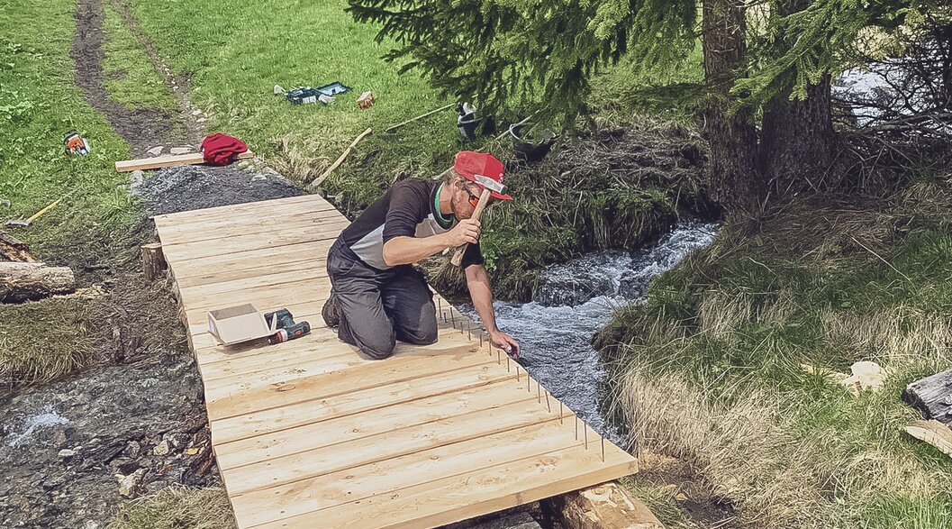 Trail Crew Davos beim Bau einer Holzbrücke | © Davos Klosters Mountains Die Trail Crew baut eine neue Holzbrücke, damit der Bach von Fussgängern und Bikern überquert werden kann. | © Davos Klosters Mountains