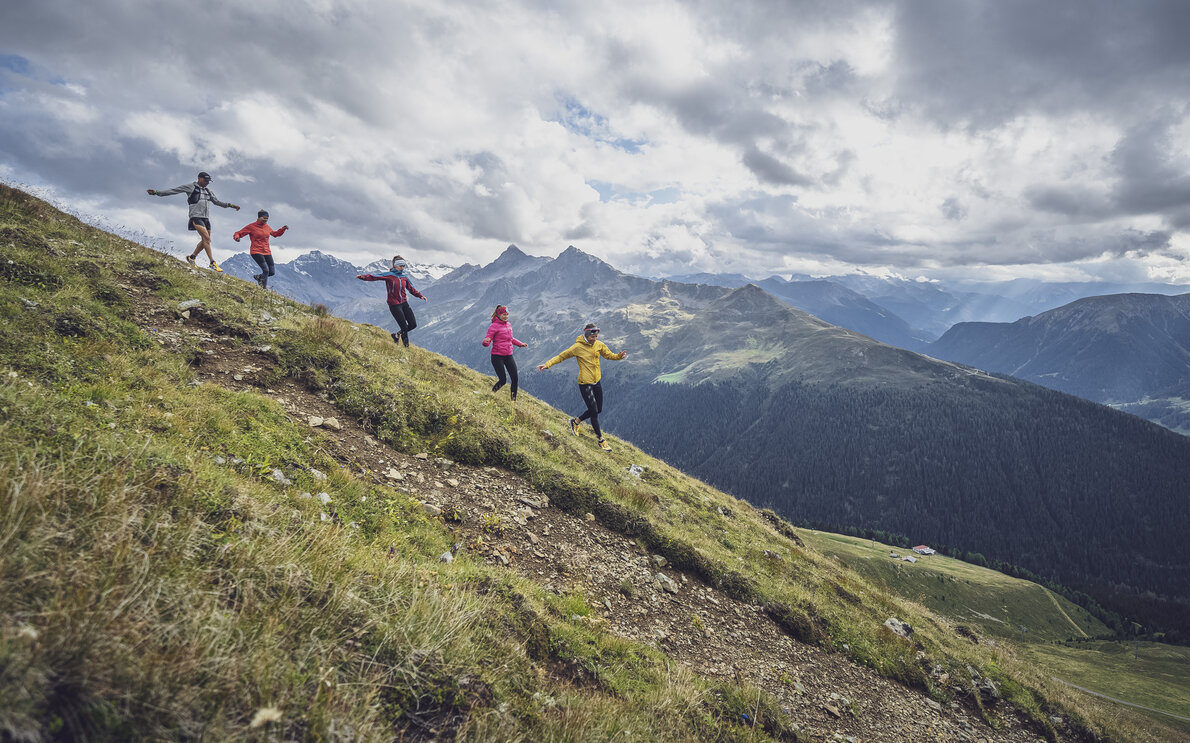 In einer Linie mit schwingenden Armen laufen die fünf Trailrunner den Hang des Jakobshorns hinab.  | © Davos Klosters Mountains