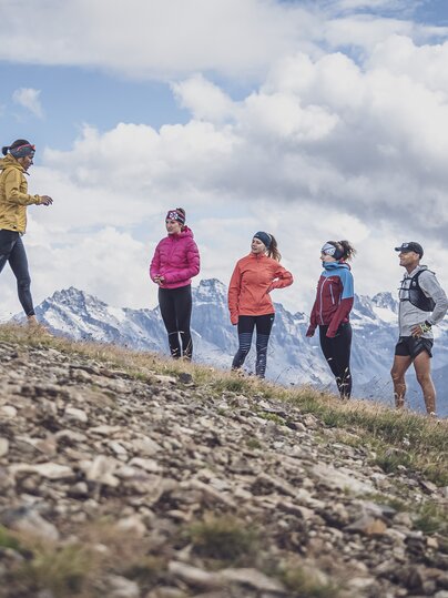 Die Trainerin zeigt die dynamische Lauftechnik für das bergab laufen vor, vier Läufer schauen zu.  | © Davos Klosters Mountains
