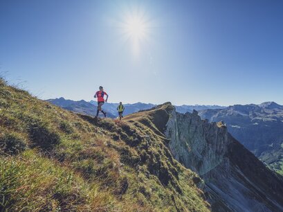 Ein Trailtrunner Paar rennt über den Grat des Geisshorns dahinter der Ausblick über das Prättigau.  | © Davos Klosters Mountains