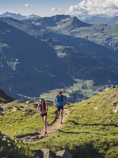 Ein Trailrunning Paar rennt auf dem Grat auf dem Jakobshorn, im Hintergrund im Tal ist der Davosersee ersichtlich.  | © Davos Klosters Mountains