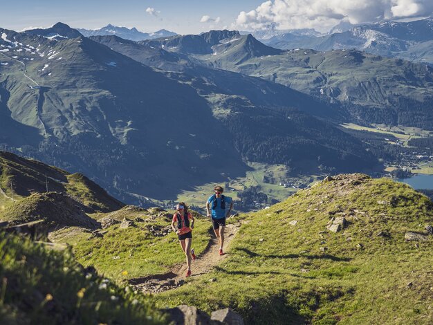 Ein Trailrunning Paar rennt auf dem Grat auf dem Jakobshorn, im Hintergrund im Tal ist der Davosersee ersichtlich.  | © Davos Klosters Mountains