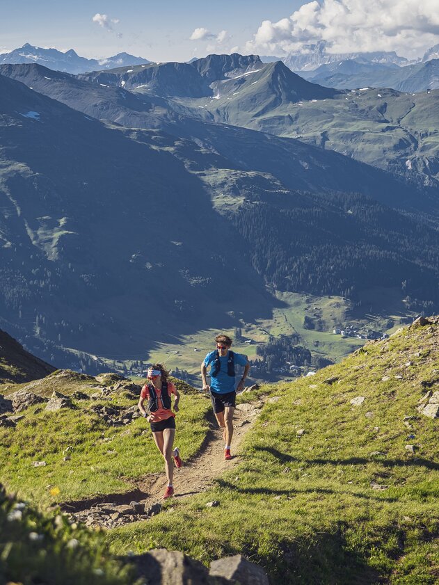 Trailrunning Jakobshorn view Davosersee | © Davos Klosters Mountains A trailrunning couple is running on the ridge of the mountain Jakobshorn, down in the valley the lake of Davos is apparent. | © Davos Klosters Mountains