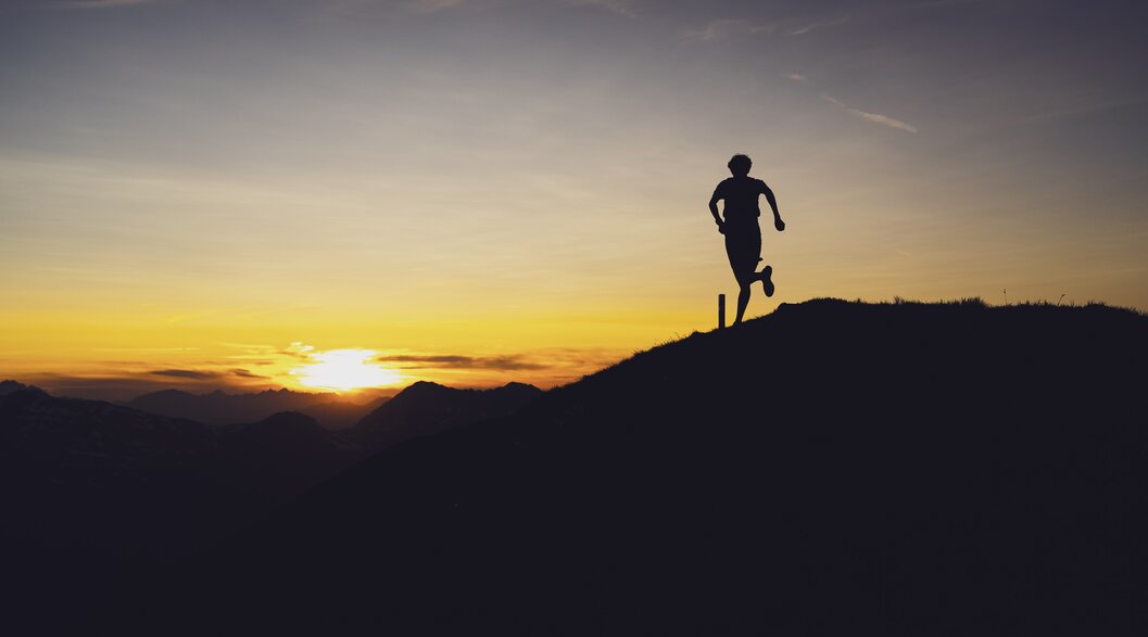 Trairunner Sonnenuntergang am Grat | © Davos Klosters Mountains Silhouette eines Trailrunners auf dem Grat vom Berg Jakobshorn, der in Richtung Sonnenuntergang rennt. | © Davos Klosters Mountains
