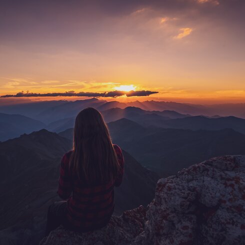 Wandrerin geniesst den Sonnenuntergang auf dem Gipfel. | © Davos Klosters Mountains 