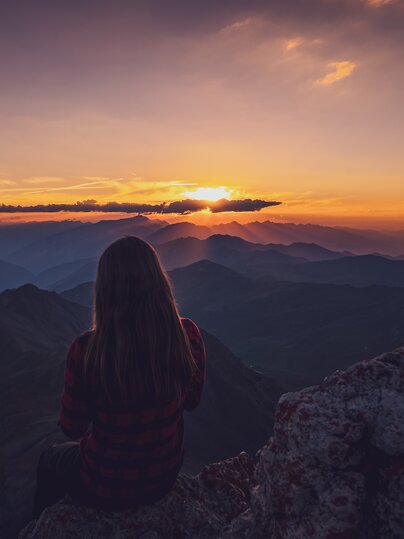 Wandrerin geniesst den Sonnenuntergang auf dem Gipfel. | © Davos Klosters Mountains 