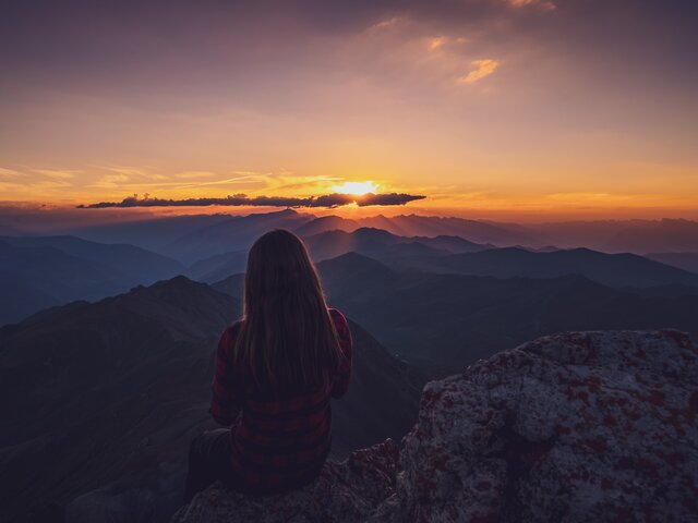 Wandrerin geniesst den Sonnenuntergang auf dem Gipfel. | © Davos Klosters Mountains 