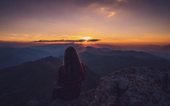 Wandrerin geniesst den Sonnenuntergang auf dem Gipfel. | © Davos Klosters Mountains 