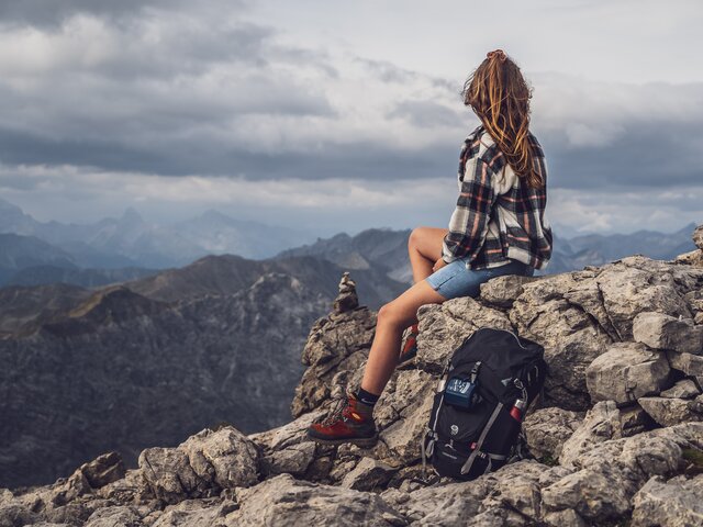 Eine Frau geniesst eine Pause vom Wandern auf einem Stein. | © Davos Klosters Mountains 