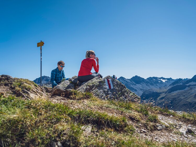 Zwei Leute picknicken auf dem Gipfel des Jatzhorns und geniessen den schönen Ausblick.  | © Davos Klosters Mountains