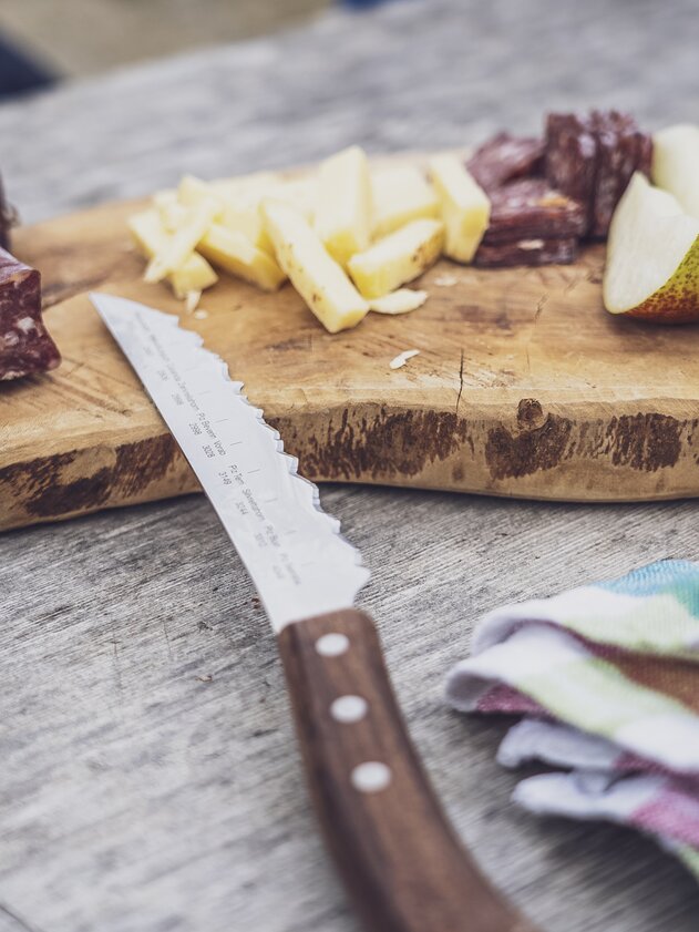 As a snack on the hike there are prepared sliced sausage, cheese and fruits on a wooden board. | © Davos Klosters Mountains