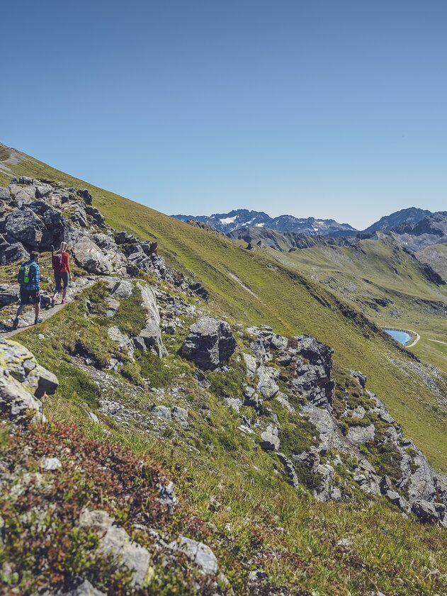 Two hikers enjoy the ridge walk from Jakobshorn to Jatzhorn looking towards the Stadlersee. | © Davos Klosters Mountains