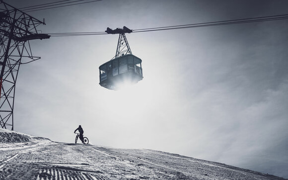 Fatbiker in the snow, gondola in the background. | © Davos Klosters Mountains