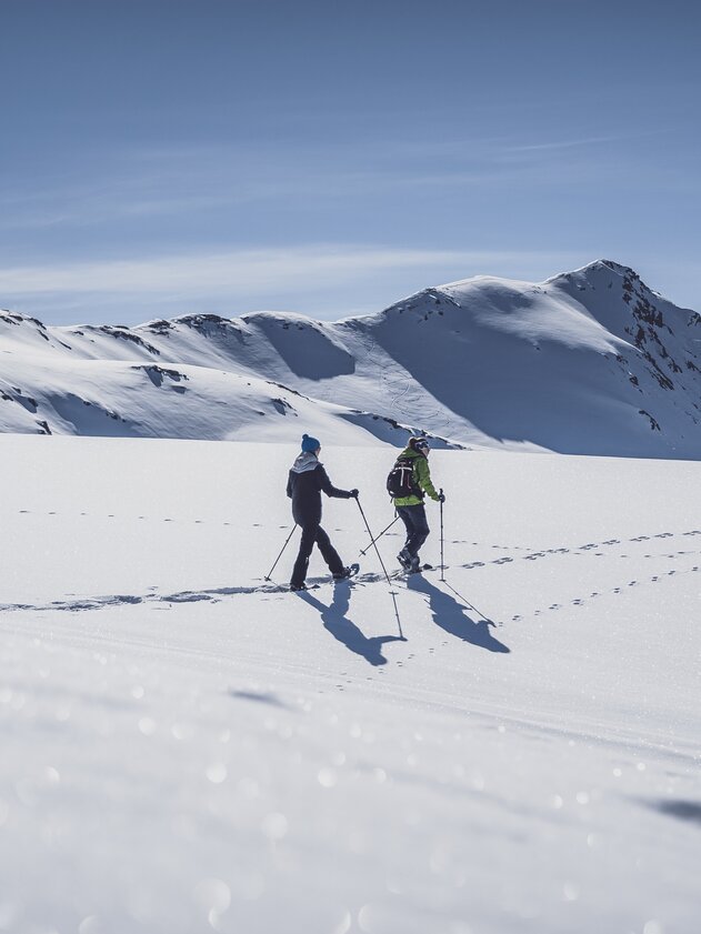 Zwei Frauen laufen mit den Schneeschuhen durch den tiefen Schnee. | © Davos Klosters Mountains