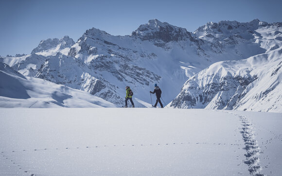 Side view of two snowshoers walking over the untouched snow on the Jakobshorn. | © Davos Klosters Mountains