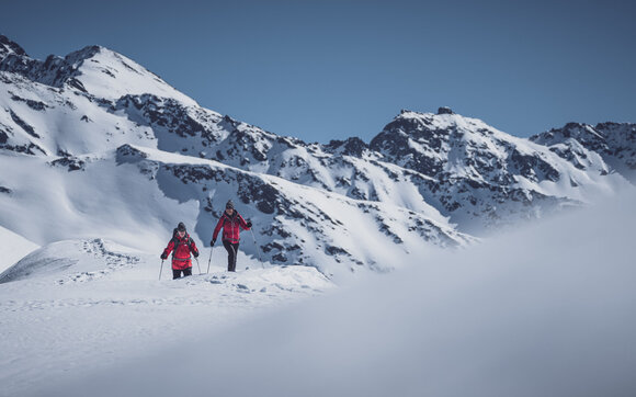 Ehepaar in rot gekleidet geniesst das Schneeschuhlaufen in Naherholungsgebiet Pischa. | © Davos Klosters Mountains