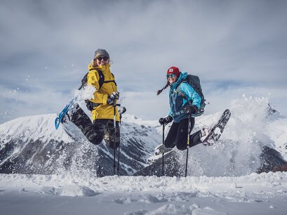Zwei Frauen springen mit ihren Schneeschuhen in die Höhe. | © Davos Klosters Mountains