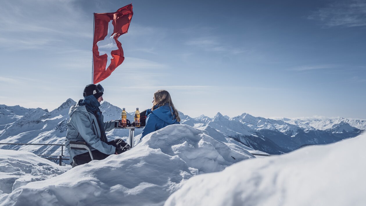 2 Wintersportler beim Rasten auf einer Terasse  | © Davos Klosters Mountains 
