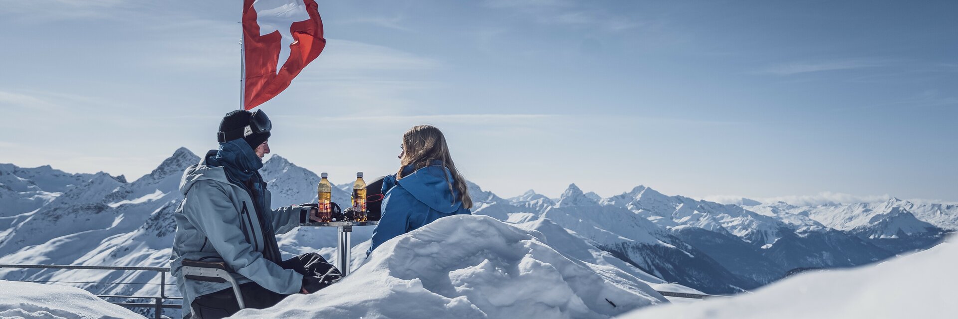2 Wintersportler beim Rasten auf einer Terasse | © Davos Klosters Mountains 2 Wintersportler beim Rasten auf einer Terasse | © Davos Klosters Mountains