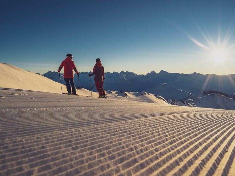 2 Skifahrer zum Sonnenaufgang auf der Piste | © Davos Klosters Mountains