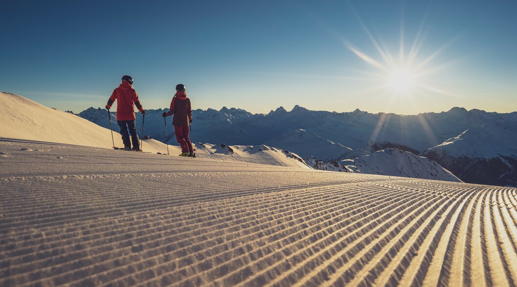 2 Skifahrer zum Sonnenaufgang auf der Piste | © Davos Klosters Mountains