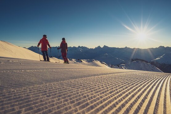 2 skiers on the piste at sunrise | © Davos Klosters Mountains