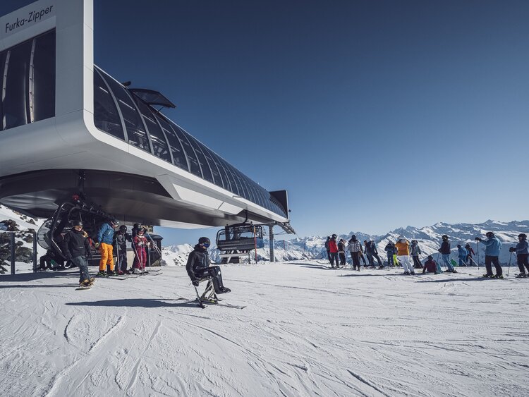 Gruppe Skifahrer und ein Monoskifahrer an der Talstation beim  Sessellift  | © Davos Klosters Mountains 