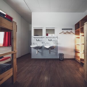 Mehrbettzimmer mit Stockbetten, Kleiderablagen und Lavabo | © Davos Klosters Mountains 