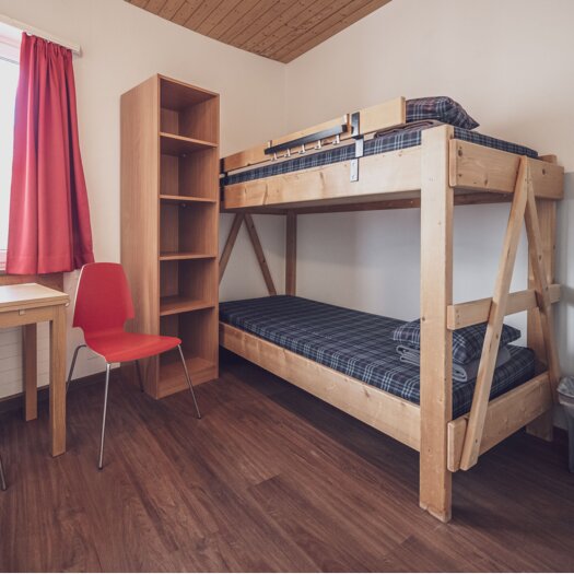 Zimmer mit Stockbett, Kleiderablage, Lavabo und Schreibtisch mit Stuhl | © Davos Klosters Mountains 