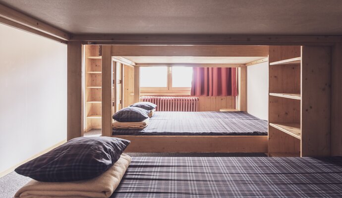 Multi-bed room with double bunk beds and clothes racks  | © Davos Klosters Mountains 